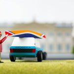 Close up of a toy figure putting the miniature wooden kayak on top of the Candylab blue suv toy