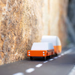 Candylab orange wooden suv toy pulling an orange caravan toy between two large rocks