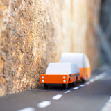 Candylab orange wooden suv toy pulling an orange caravan toy between two large rocks