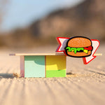 Close up of the Candylab wooden burger shack toy on some sand
