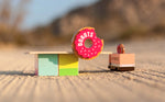 Candylab eco-friendly wooden donut shack toy set on a sandy background next to a toy donut truck