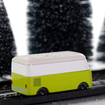 Side view of the CandyLab green VW T1 Campervan - driving through a snowy forest. 