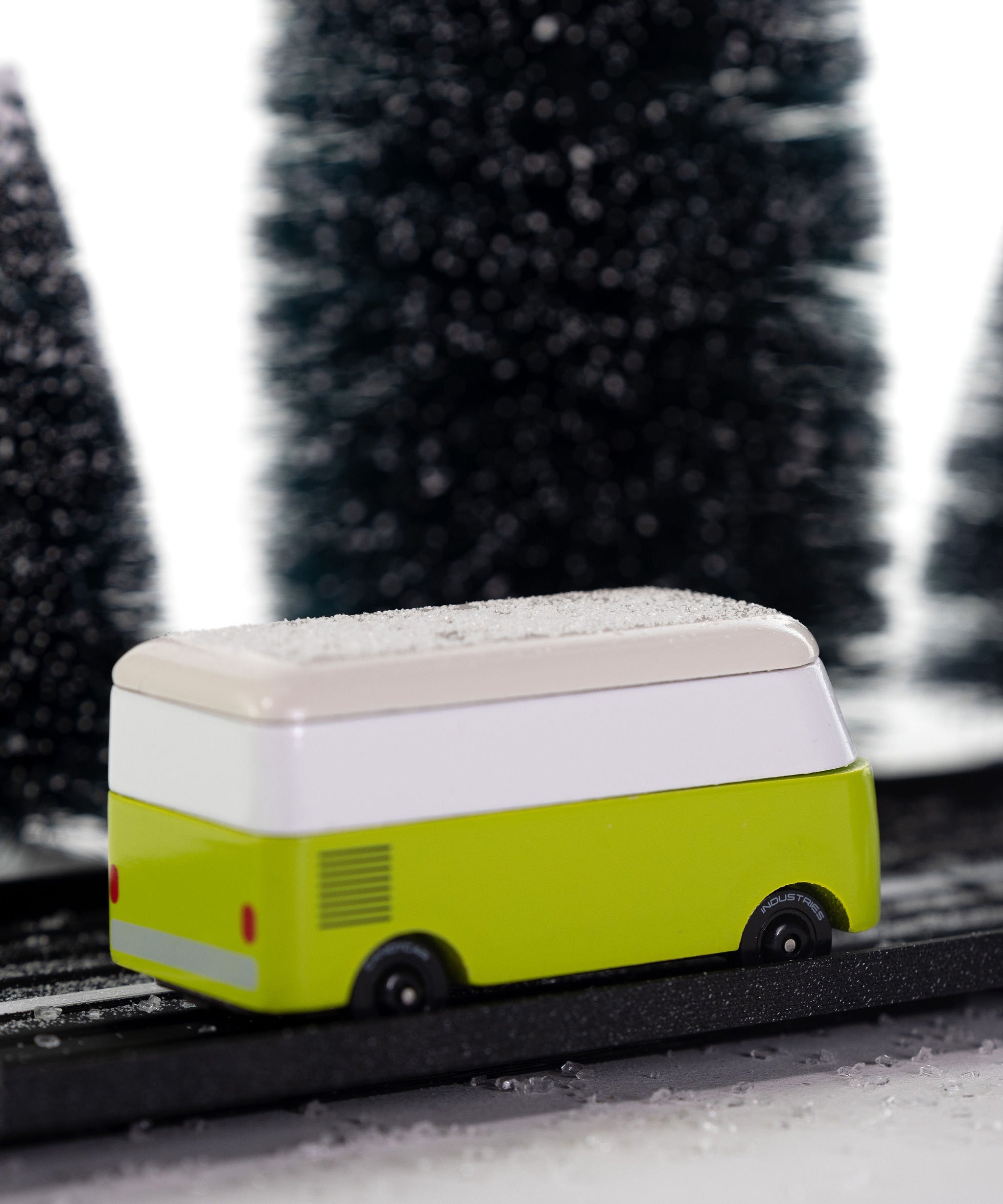 Side view of the CandyLab green VW T1 Campervan - driving through a snowy forest. 