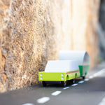 Green candylab suv car toy pulling a little caravan on a rubber road between 2 rocks