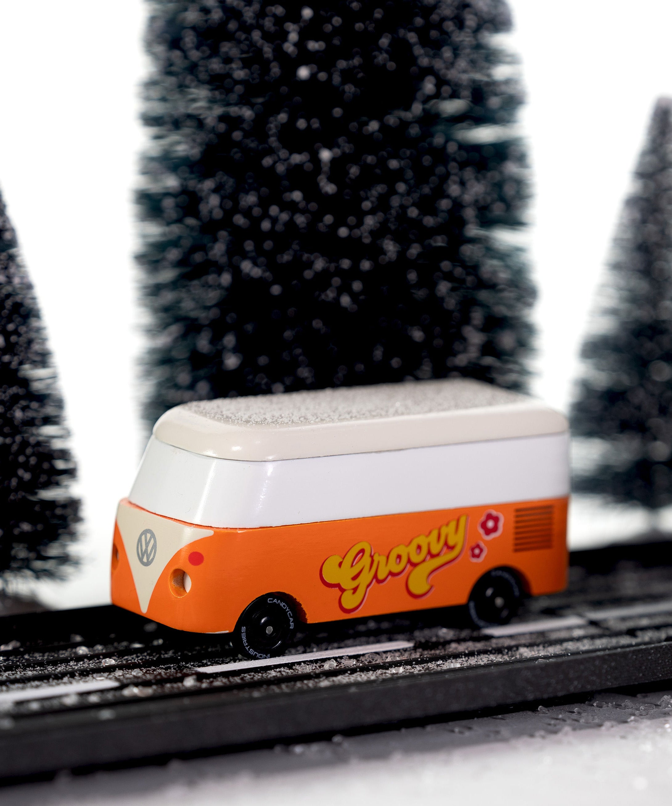 CandyLab orange VW T1 Campervan with 'Groovy' text on the side in a 60s font - driving through a snowy forest.
