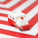 Candylab childrens small wooden ambulance toy on a red and white striped background