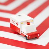 Candylab childrens small wooden ambulance toy on a red and white striped background