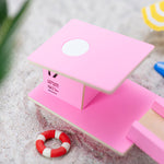 Close up of the Candylab slotting wooden beach tower toy on a sandy background next to some miniature umbrellas