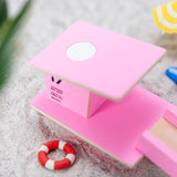 Close up of the Candylab slotting wooden beach tower toy on a sandy background next to some miniature umbrellas