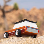 Close up of the Candylab solid wooden big sur car toy on a large rock in front of a beige background
