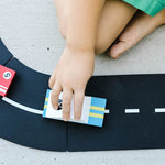 Close up of a child pushing the Candylab eco-friendly wooden racing car toy on a road set
