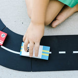 Close up of a child pushing the Candylab eco-friendly wooden racing car toy on a road set