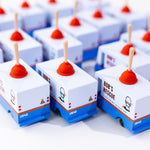 Group of Candylab handmade wooden plumbing truck toys lined up on a white background