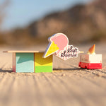 The Candylab Ice Cream Food Shack next to a ice cream truck on a sandy surface.
