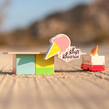 The Candylab Ice Cream Food Shack next to a ice cream truck on a sandy surface.