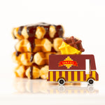 Close up of the Candylab wooden waffle toy truck next to a pile of chocolate waffles on a white background