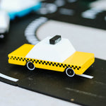 Close up of the Candylab wooden taxi toy vehicle on a black toy road set