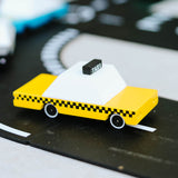 Close up of the Candylab wooden taxi toy vehicle on a black toy road set