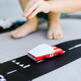 Close up of the Candylab red racing car toy on a rubber road set in front of a childs feet