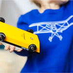 Close up of a child holding a Candylab Doc Ryder yellow and black muscle car toy