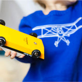 Close up of a child holding a Candylab Doc Ryder yellow and black muscle car toy