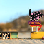 Close up of the Candylab wooden motel toy set on some sand in front of a large rock