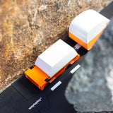 Orange suv diecast toy car pulling an orange caravan toy between two large rocks