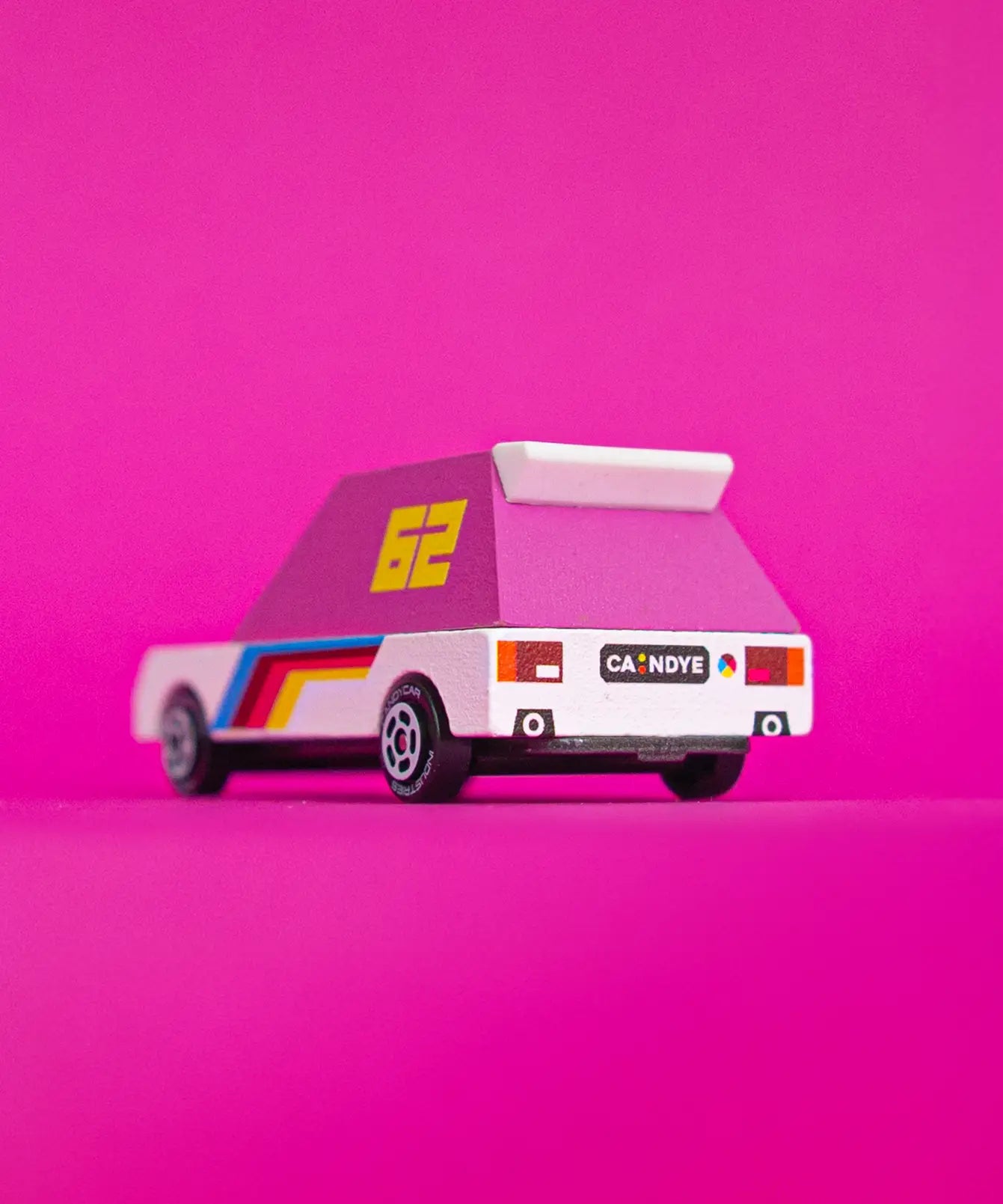 Back of the Candylab pink 62 racer toy car with a white body, pink windows and decals against a bright pink background