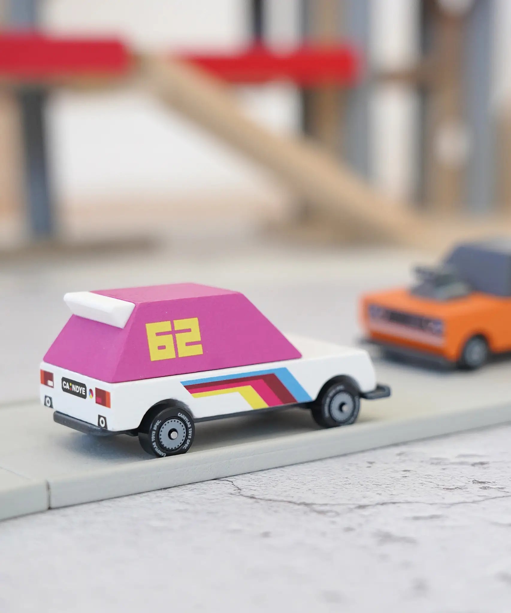Candylab wooden diecast pink 62 racer toy car on a play road with another car in the background