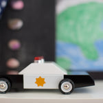 Side of the Candylab childrens diecast wooden toy on a white worktop in front of a blue and green background