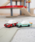 Candylab wooden diecast tora drift teal toy car next to a hachigo red toy car on a play road