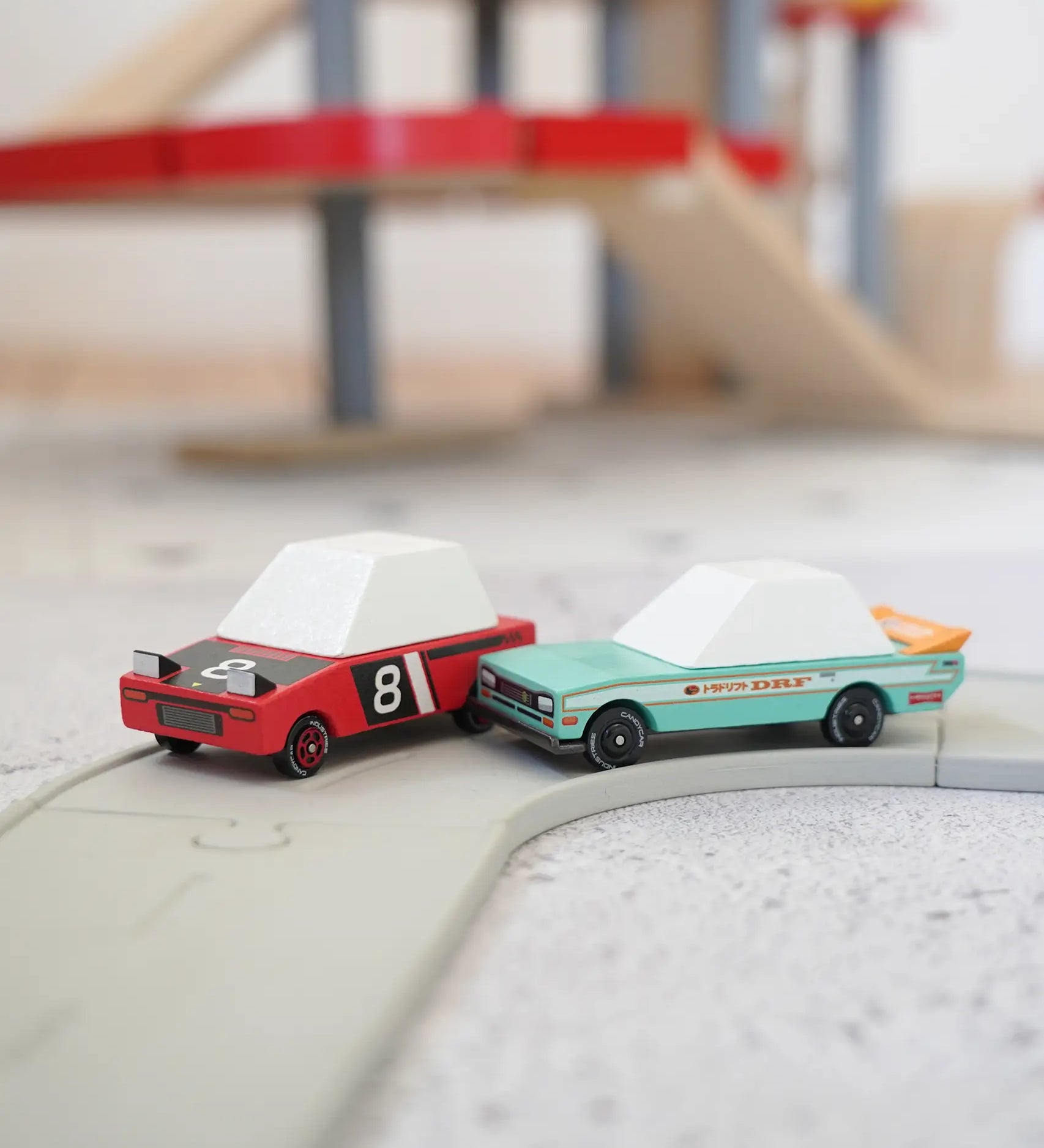 Candylab wooden diecast tora drift teal toy car next to a hachigo red toy car on a play road