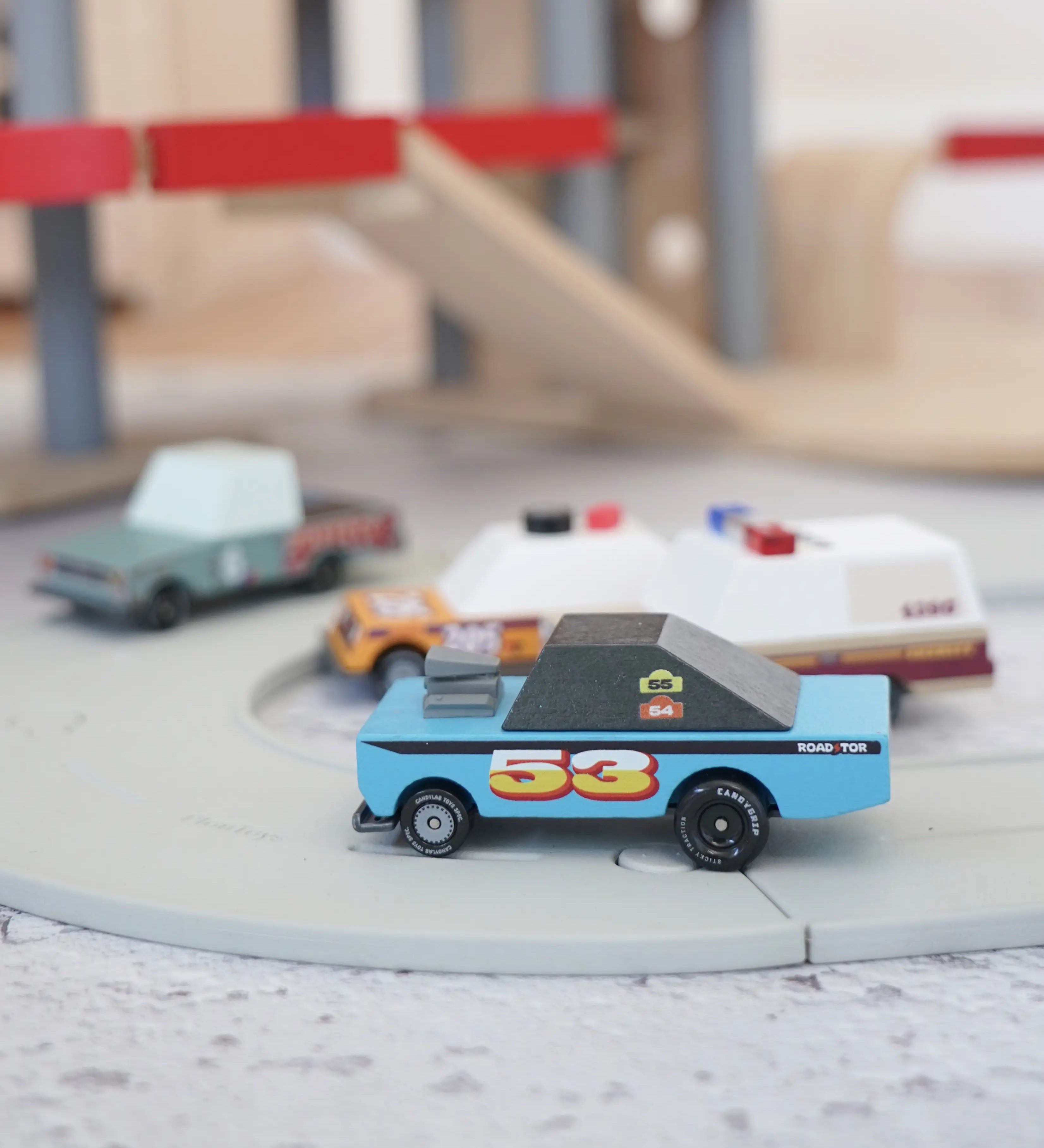 4 Candylab rust patrol toon cars on a play road with a parking garage in the background.