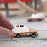 Adult hand pushing a orange Candylab rust patrol car on a play road showing scale 