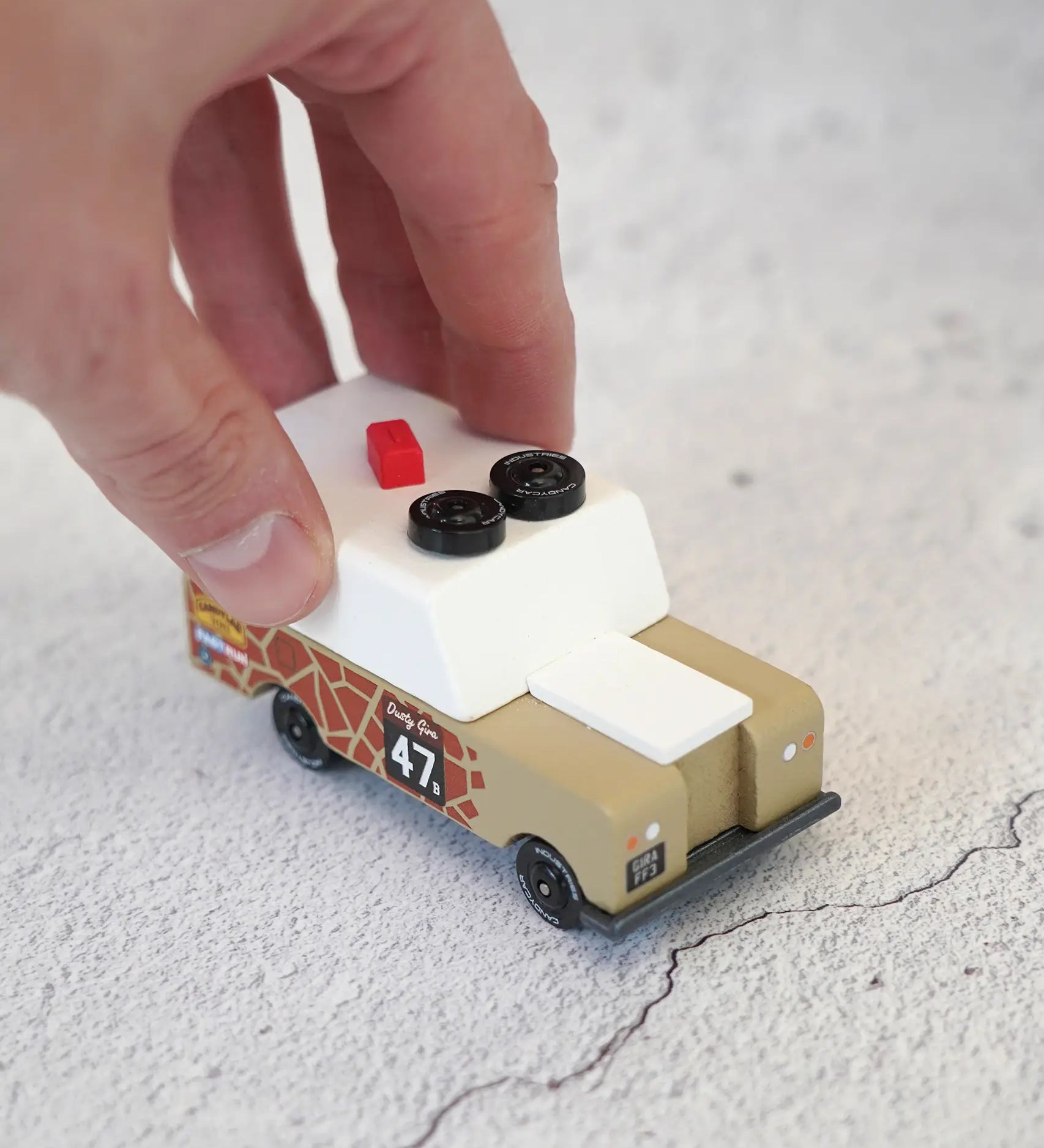 Adult hand pushing the Candylab wooden diecast safari Gira drifter adventure toy truck showing scale
