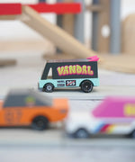 Candylab seafoam vandal van on a playroad with a parking garage in the background.
