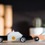 Candylab wooden collectable police cruiser toy on a wooden table in front of a black background