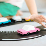 Close up of childs hand reaching for the Candylab handmade wooden pink sedan candycar on a play road set