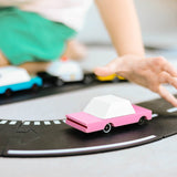 Close up of childs hand reaching for the Candylab handmade wooden pink sedan candycar on a play road set