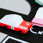 Close up of the Candylab red racing car and pink sedan diecast toys on a black toy road set