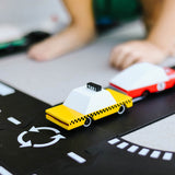 Close up of a child playing with the Candylab wooden taxi toy car on a black toy road set
