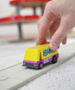 Adult hand holding a Candylab wooden diecast yellow speed vandal toy van showing scale