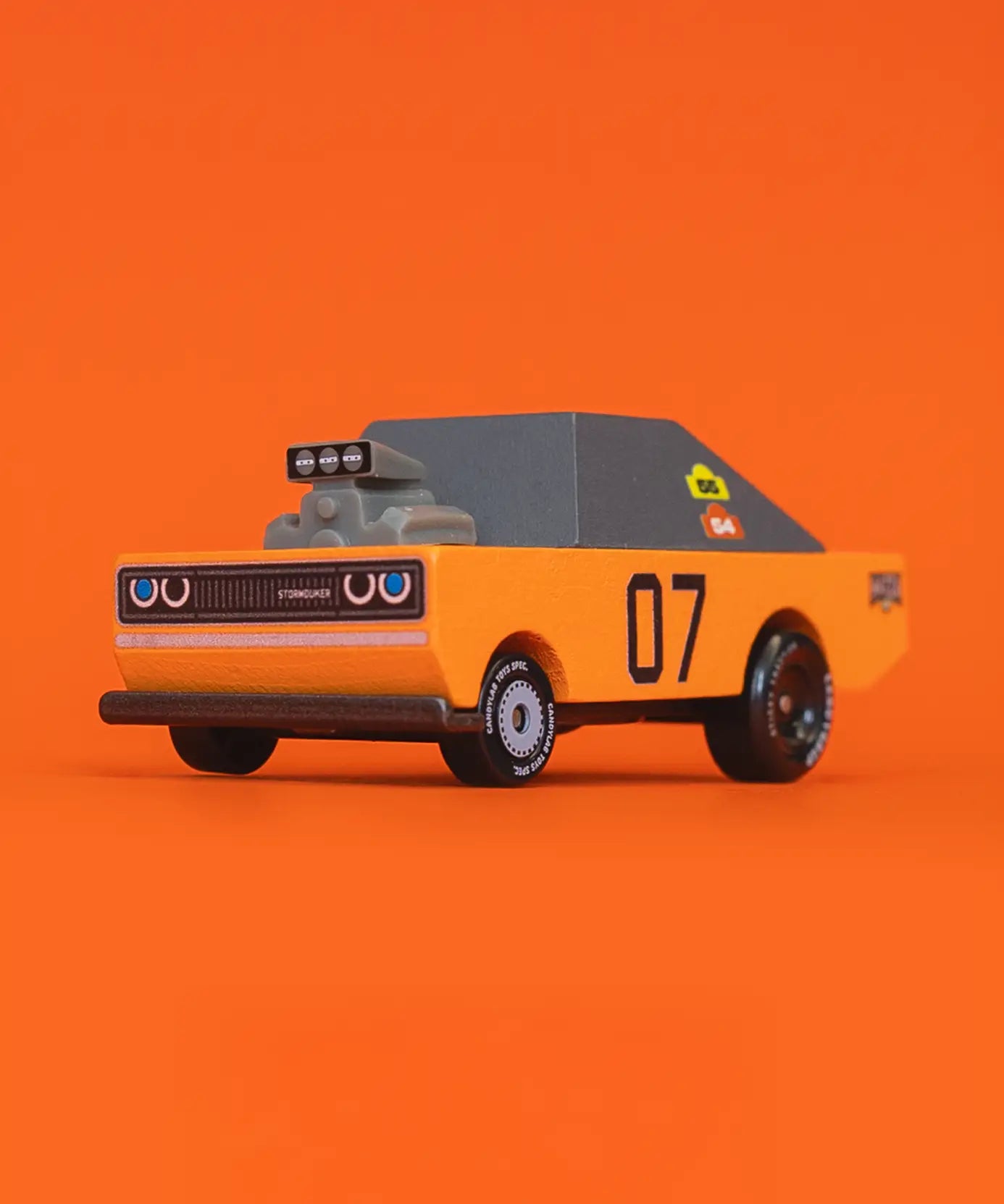Front of Candylab stormduker muscle toy car with a orange body, grey windows and decals infront of orange background