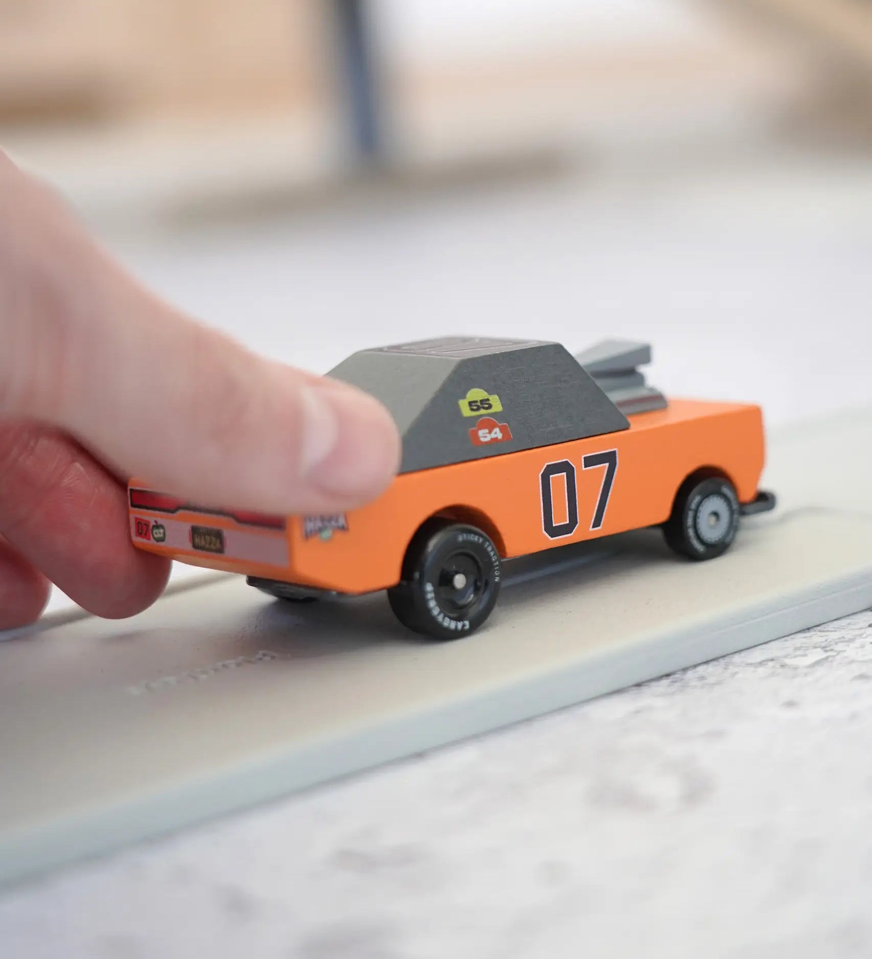 Adult hand pushing the Candylab wooden diecast stormduker orange muscle toy car showing scale