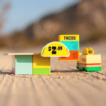 The Candylab Taco Food Shack next to the taco truck on a sandy surface. 