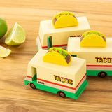 3 Candylab solid wooden taco van toys on a wooden chopping board next to a sliced lime