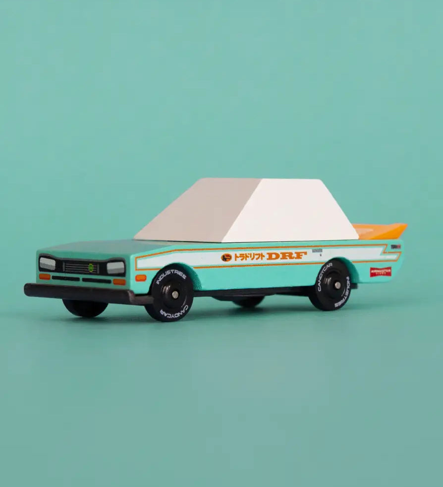 Candylab wooden diecast teal tora racer toy car in front of a light green background.