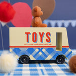 CandyLab cream and blue CandyVan with a brown teddy bear on the roof with Toys text logo in red on the side - on a blue checked cloth.