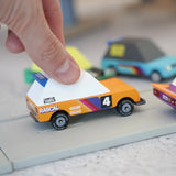 Adult hand holding a orange racing car from the Candylab Tokyo heat toon cars set on a play road showing scale