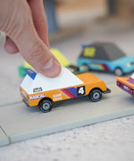 Adult hand holding a orange racing car from the Candylab Tokyo heat toon cars set on a play road showing scale